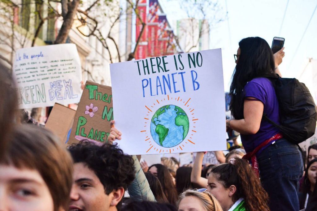 Students at a rally with someone holding a sign with the Earth on it that says "There is no planet B"